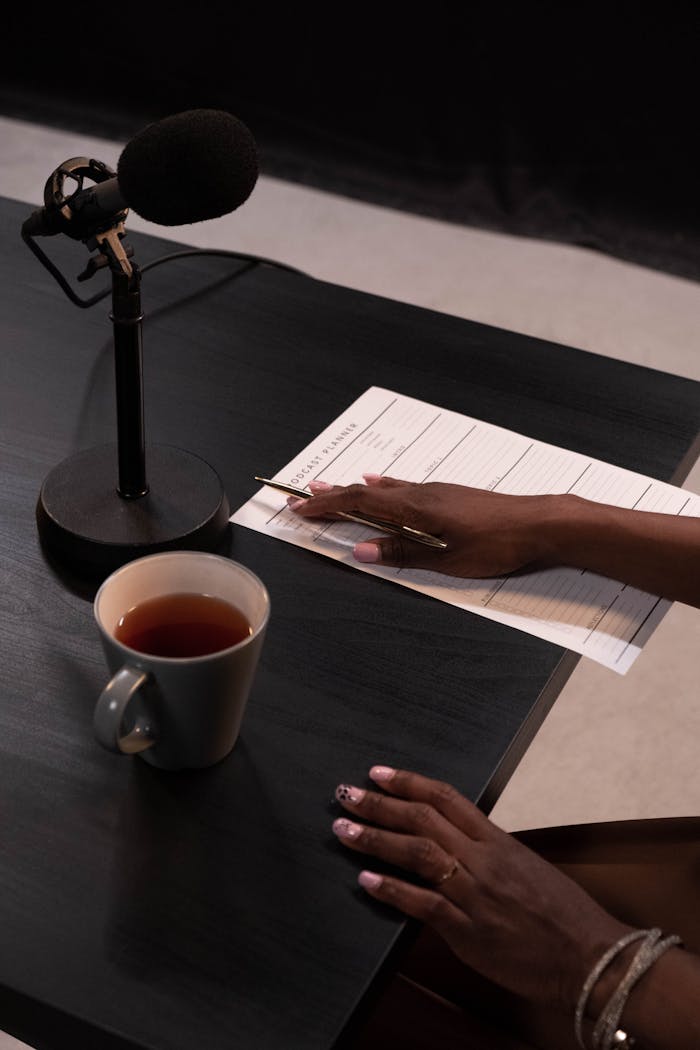 A cozy podcast recording setup with tea, notes, and a microphone on a stylish black table.